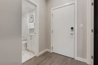 a white bathroom with a toilet and a door at Free Heated Parking, Quick DT Access in Calgary