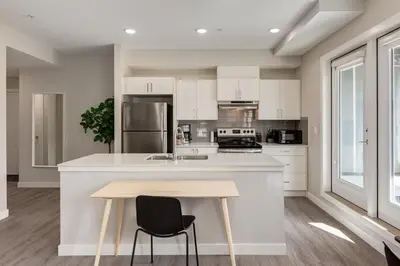 a kitchen with white cabinets and a wooden table at Free Heated Parking, Close to DT, Pet Friendly in Calgary
