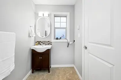 a white bathroom with a sink and a mirror at Home away from Home in Victoria