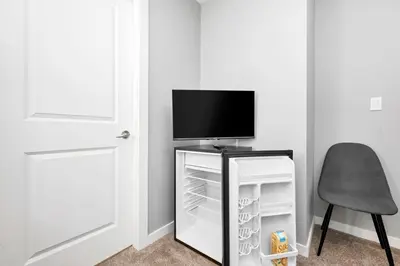 a room with a tv and a chair and a refrigerator at Home away from Home in Victoria