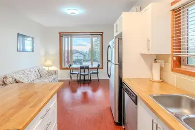 a kitchen with a refrigerator and a table in it at Beaches Downtown Suite In Sechelt in Sechelt