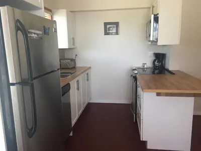 a kitchen with a stainless steel refrigerator and white cabinets at Beaches Downtown Suite In Sechelt in Sechelt
