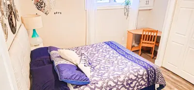 a bedroom with a bed and a table and a window at Casa Andrei in Edmonton