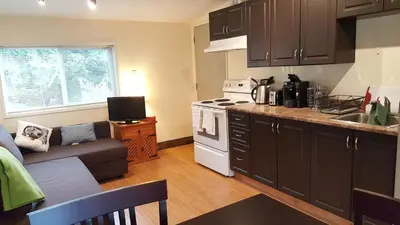 a kitchen with a couch and a stove top oven at Cozy Quiet Suite with Private Hot Tub with Ocean Views in Nanaimo