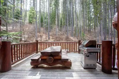 a grill on a wooden deck with a forest at Ravenwood Cabin by StayIn in Panorama
