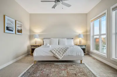 a white bedroom with a bed and two windows at Golden View Manor in Calgary
