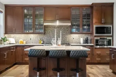 a kitchen with wooden cabinets and a island with bar stools at Golden View Manor in Calgary