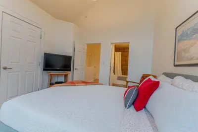 a bedroom with two white beds and a television at Alpine Village Condo by Canadian Rockies Vacation Rentals in Canmore