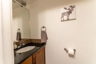 a bathroom with a sink and a deer picture on the wall at Alpine Village Condo by Canadian Rockies Vacation Rentals in Canmore