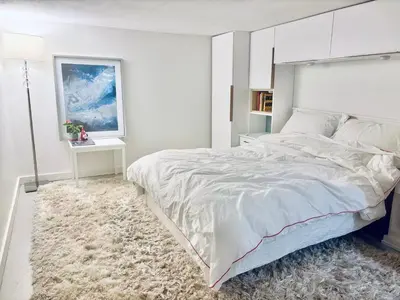 a white bedroom with a large bed and a rug at Private Suite With Spacious Yard in Vancouver