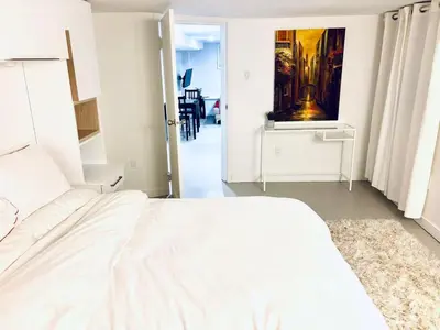 a bedroom with a white bed and a painting on the wall at Private Suite With Spacious Yard in Vancouver