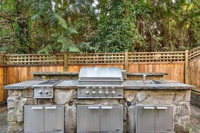 a outdoor kitchen with a stove and a sink at Elegant West Vancouver Estate with Ocean Views in West Vancouver