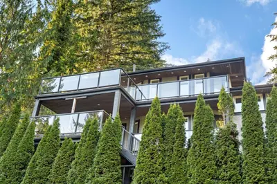 a house with a glass facade and trees at Elegant West Vancouver Estate with Ocean Views in West Vancouver