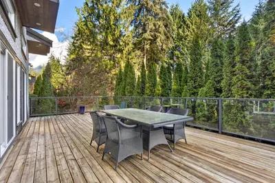 a patio with a table and chairs on a wooden deck at Elegant West Vancouver Estate with Ocean Views in West Vancouver