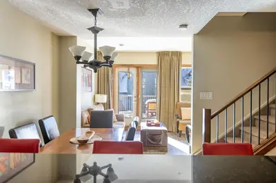 a living room with red chairs and a dining room at Stunning Central Canmore Condo in Canmore
