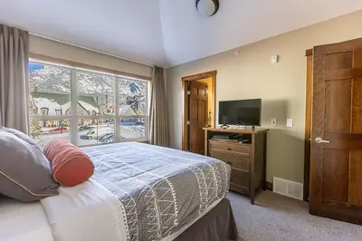 a bedroom with a bed and a tv and a window at Stunning Central Canmore Condo in Canmore