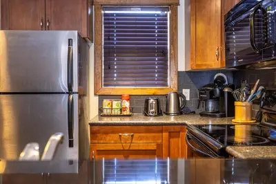 a kitchen with a stainless steel refrigerator and wooden cabinets at Stunning Central Canmore Condo in Canmore