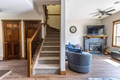 a living room with stairs and a couch and a tv at Newly Renovated Rocky Mountain Canmore Chalet in Canmore