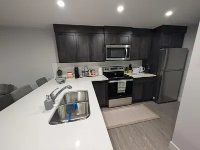 a kitchen with wooden cabinets and a counter top at DaraJay Cozy Home in Calgary