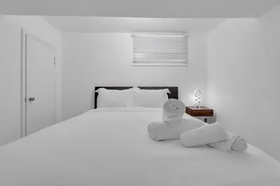 a white bedroom with a large bed with towels on it at 5 bed Luxury Home Steps to DT, River and Hospital in Calgary