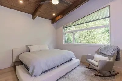 a bedroom with a bed and a chair and a window at Large Modern Home in Squamish in Squamish