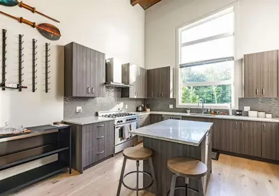 a kitchen with wooden cabinets and a large window at Large Modern Home in Squamish in Squamish