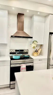 a kitchen with white cabinets and a stove top oven at 3 Story Luxury Cozy Sleek Home in Edmonton