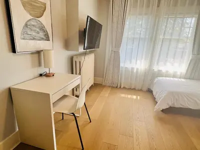 a bedroom with a desk and a bed and a television at West King Edward Luxury Guest Home in Vancouver