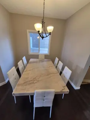 a dining room with a large table and white chairs at Sean Comfy Home in Edmonton