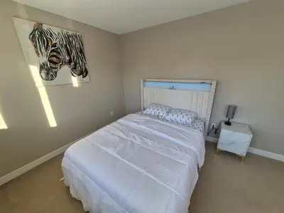 a bedroom with a bed and a painting on the wall at Sean Comfy Home in Edmonton