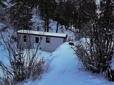 a small shed in the snow with snow on it at Runaway Express Coach in Oliver