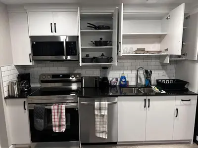 a kitchen with white cabinets and stainless steel appliances at Newly Built 2-Bedroom, 2 full bath Basement Suite in Calgary