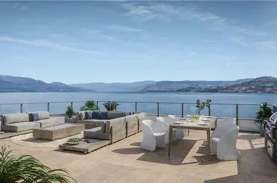 a patio with couches and a table and the water at Beach Lake Resort in Kelowna