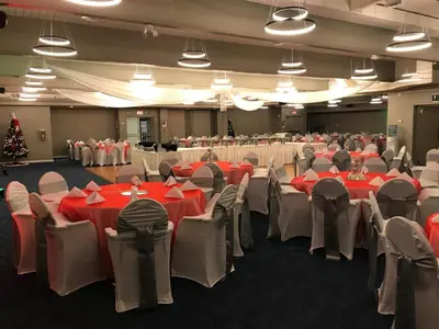 a room filled with tables and chairs with red tablecloths at Stonebridge Hotel in Fort McMurray