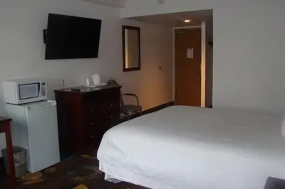 a bedroom with a bed and a tv on the wall at Stonebridge Hotel in Fort McMurray