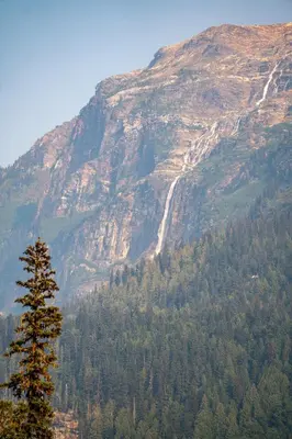 a mountain with a waterfall and a tree at River Safari Bear Den in Blue River