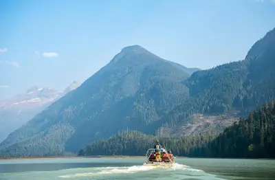 a boat on a lake with mountains in the background at River Safari Bear Den in Blue River