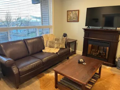 a living room with a leather couch and a fireplace at Peaks & Waters at Harrison Mills in Agassiz