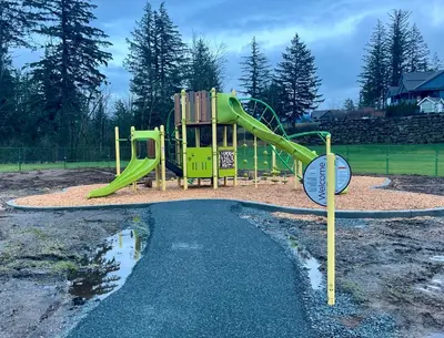 a playground with a green slide in a park at Peaks & Waters at Harrison Mills in Agassiz