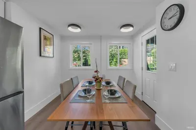 a dining room with a table and a clock on the wall at Cozy three bedroom House in Vancouver West in Vancouver