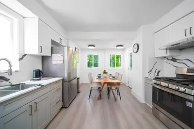 a kitchen with white cabinets and a wooden table at Cozy three bedroom House in Vancouver West in Vancouver