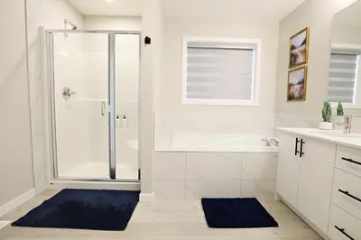 a white bathroom with a shower and a sink at Edgemont Escape Large Groups, River Cree, WEM, Disney in Edmonton