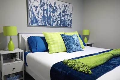 a bedroom with a bed with blue and yellow pillows at Edgemont Escape Large Groups, River Cree, WEM, Disney in Edmonton
