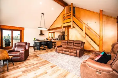 a living room with two chairs and a staircase at River Safari Eagles Nest in Blue River
