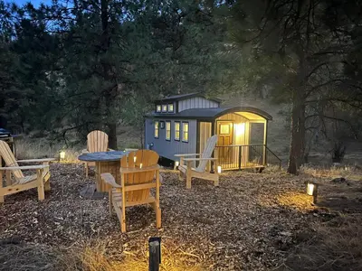 a tiny house with chairs and a table and lights at Sagebrush Caboose in Okanagan Falls