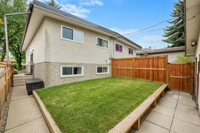 a backyard with a wooden fence and a lawn at Comfy, Cozy, Central Calgary, 2BR and 1BTH in Calgary