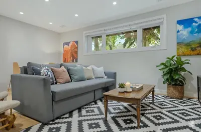 a living room with a gray couch and a table at Cozy and Welcoming 2BR Basement Suite In The Heart of Calgary in Calgary