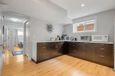 a kitchen with wooden cabinets and a microwave at Cozy and Welcoming 2BR Basement Suite In The Heart of Calgary in Calgary
