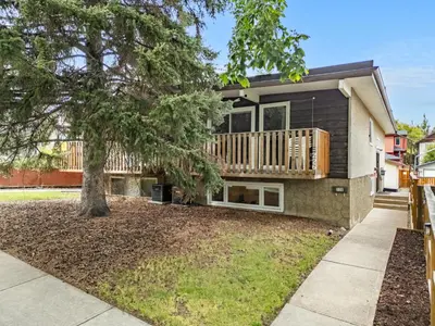 a house with a deck and a tree at Cozy and Welcoming 2BR Basement Suite In The Heart of Calgary in Calgary