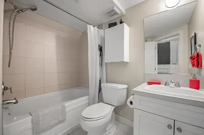 a white bathroom with a toilet and a sink at Cozy and Welcoming 2BR Basement Suite In The Heart of Calgary in Calgary